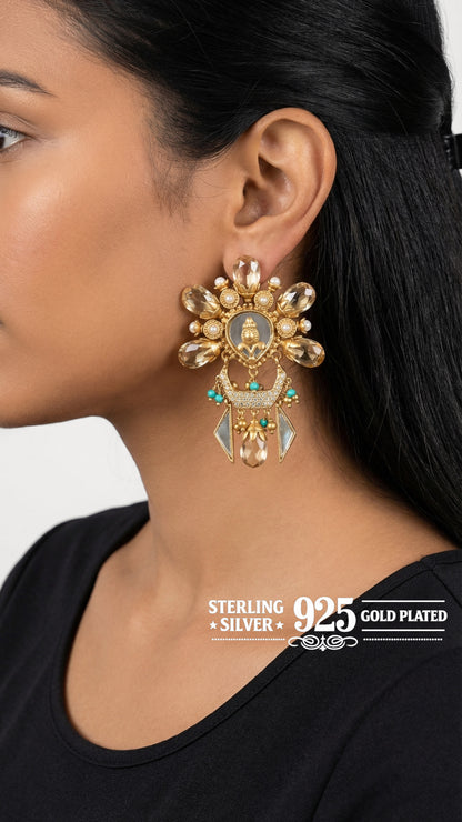 Gold earrings worn by a person with text indicating 'Sterling Silver 925 Gold Plated' on a plain background.