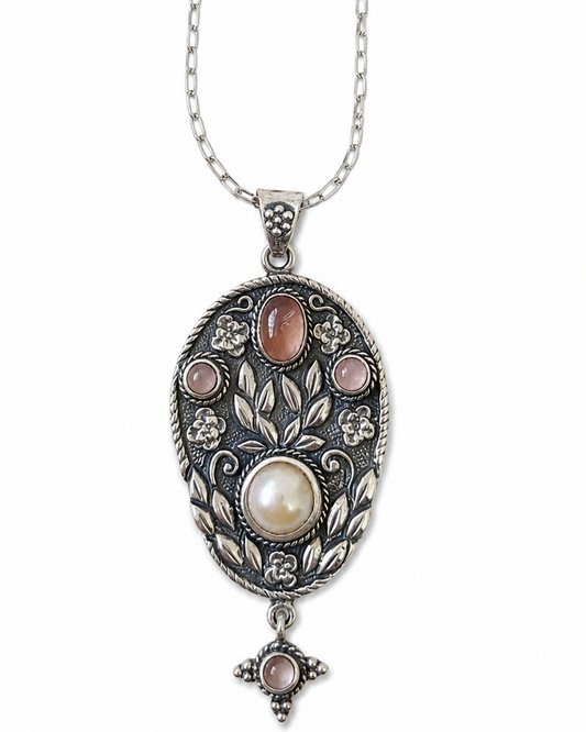 Silver necklace with an ornate pendant featuring a pearl and gemstones on a white background